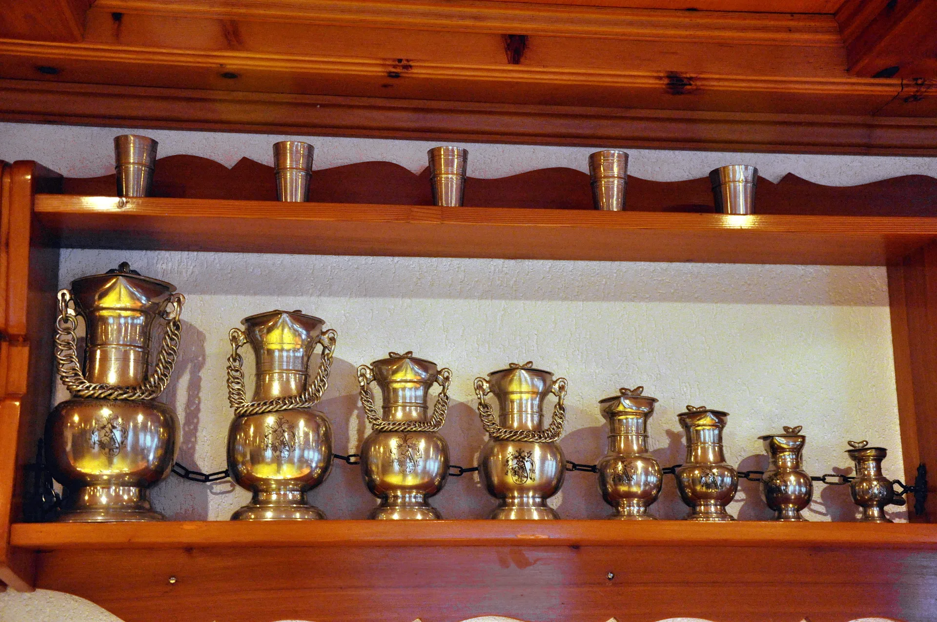 Traditionelle Zinnkannen und Becher auf Holzregal im Hotel Alpenblick