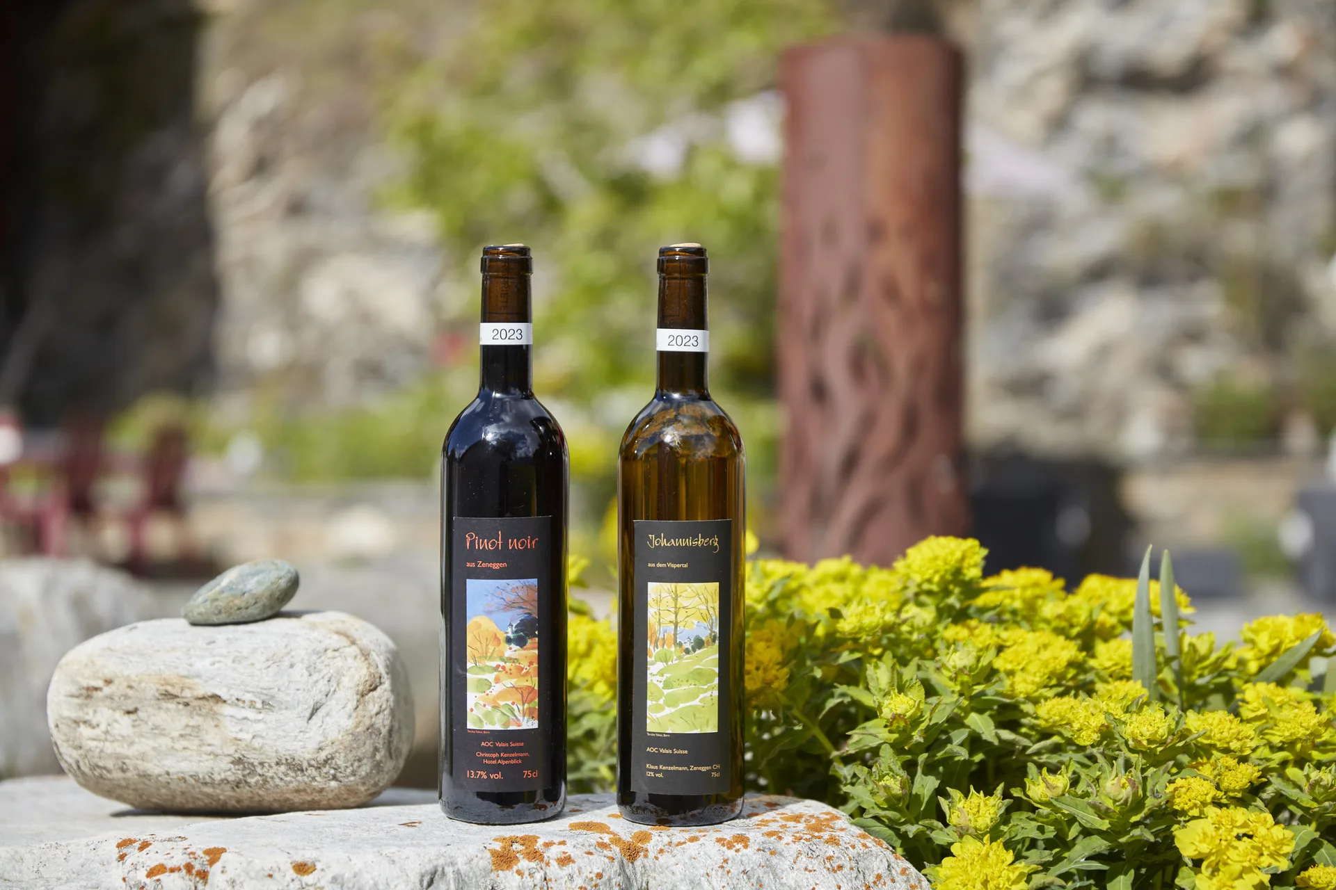 Deux bouteilles Eigänä 2023 – Pinot Noir et Johannisberg sur une pierre naturelle avec des fleurs